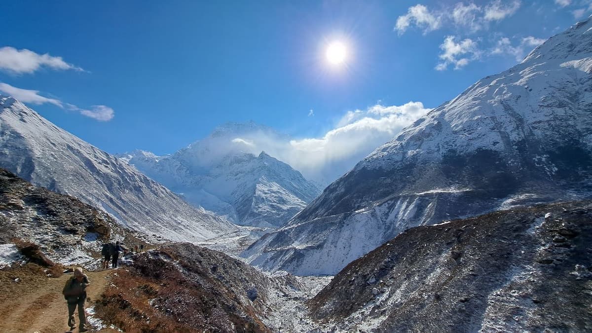 Trekkers walking a high mountain trail near Samdo with snow-covered peaks of the Manaslu region