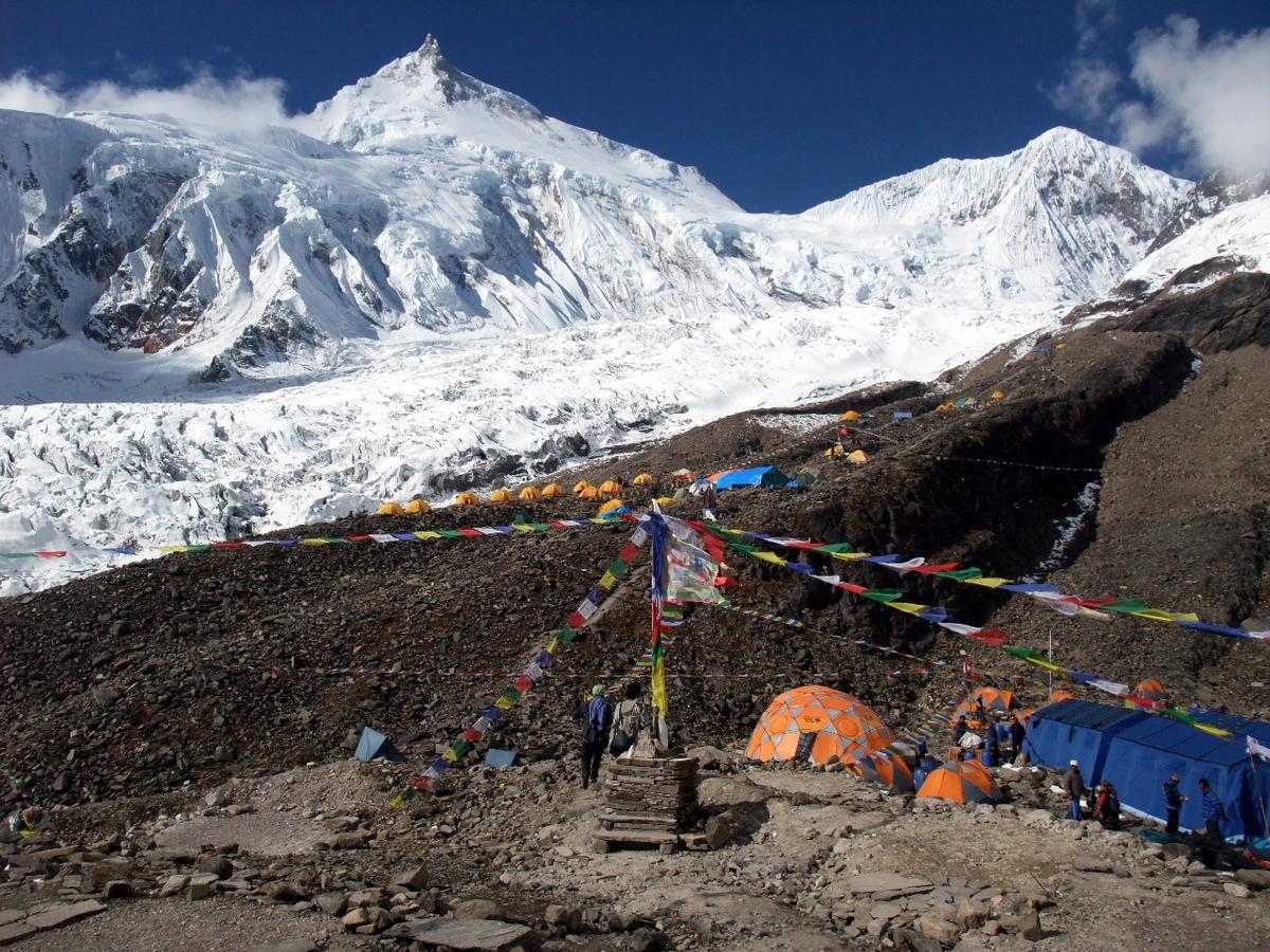 Manaslu Base Camp with tents, prayer flags and the Manaslu glacier below the summit